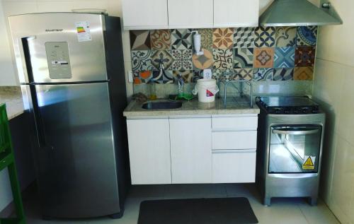 a small kitchen with a refrigerator and a stove at Linda Casa de Praia em Itacimirim in Itacimirim