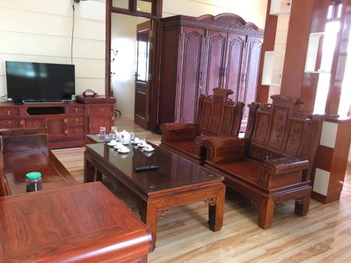a living room with wooden furniture and a flat screen tv at Duong Ha Hotel in Cao Bằng