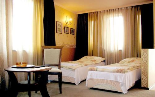 ヴェリコ・タルノヴォにあるGuest Rooms Bela Nedaのベッド2台とテーブルが備わるホテルルームです。
