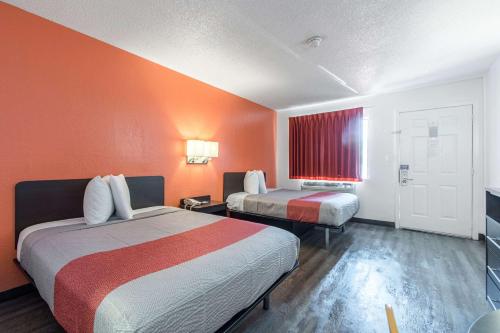 a hotel room with two beds and orange walls at Motel 6-Norcross, GA - Atlanta Northeast in Norcross