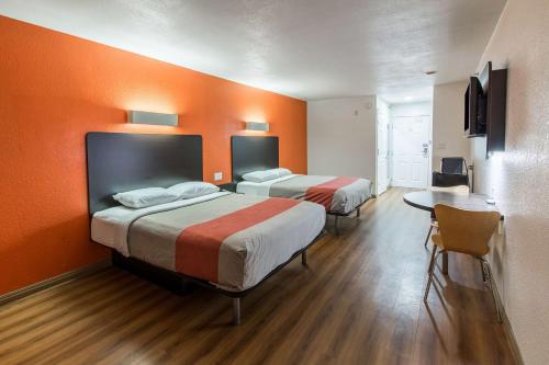two beds in a room with orange walls at Motel 6-Hutchins, TX in Hutchins