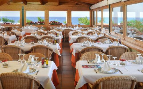 un restaurante con mesas y sillas blancas y ventanas en Camping Bon Repós, en Santa Susanna
