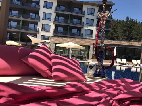 a bed with pink pillows next to a swimming pool at Hotel Arte SPA & Park in Velingrad