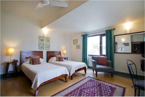 a bedroom with two beds and a chair and a window at Zaza Stay in New Delhi