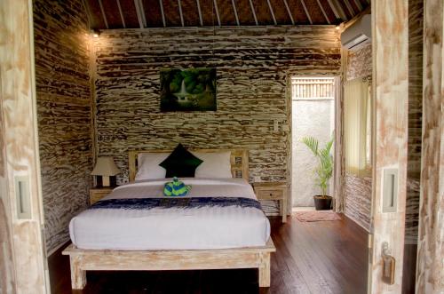 a bedroom with a bed and a stone wall at Kakiang Guesthouse in Nusa Lembongan
