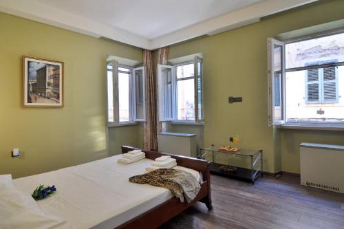 a bedroom with a bed in a room with windows at Lemonia Luxury Apartment in Corfu Town