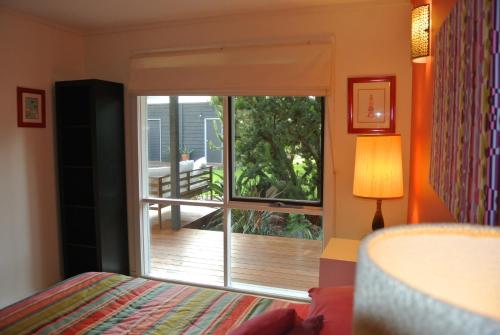 a bedroom with a window with a view of a deck at Clambake Beach House in Cape Woolamai