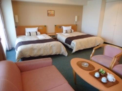 a hotel room with three beds and a couch at Kuretake Inn Asahikawa in Asahikawa