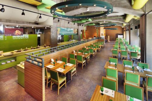 a restaurant with wooden tables and green chairs at Hanwha Resort Gyeongju in Gyeongju