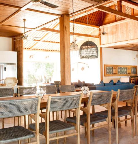 a dining room with tables and chairs and a couch at Villa Pulau Cinta Boutique Suites in Gili Meno