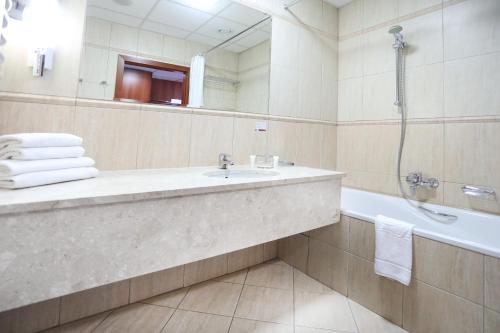 a bathroom with a sink and a tub and a mirror at Hotel Belweder in Ustroń