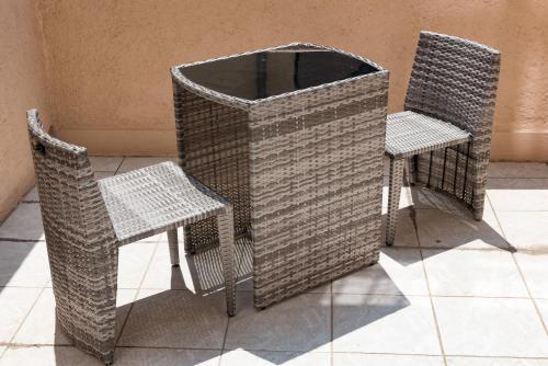 two wicker chairs and a table and two chairs at Hotel Le 21 in Saint-Raphaël