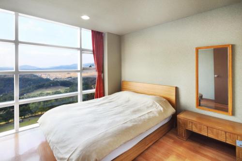 - une chambre avec un lit et une grande fenêtre dans l'établissement Hanwha Resort Gyeongju, à Gyeongju