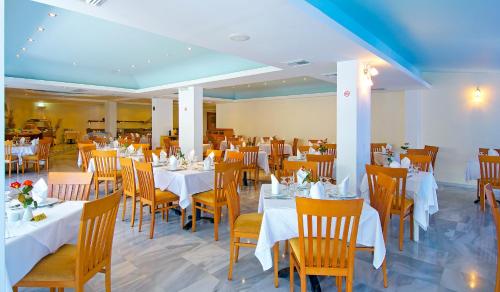 a dining room with white tables and chairs at Rethymno Mare Royal & Water Park in Skaleta
