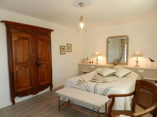 une chambre avec un lit avec un miroir et une chaise dans l'établissement La Sembelie, à Carsac-Aillac