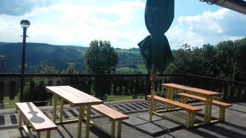 two benches and a umbrella on top of a balcony at Penzion Pohlednička in Benecko