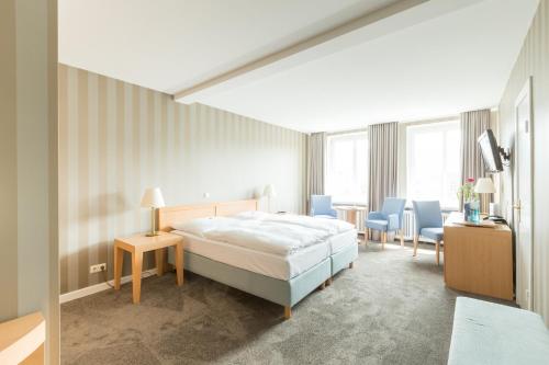 a bedroom with a bed and a table and chairs at Relexa Hotel Bellevue an der Alster in Hamburg