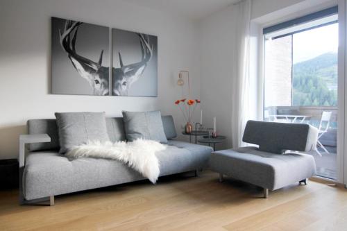 ein Wohnzimmer mit einem Sofa und einem Stuhl in der Unterkunft Apartment Bergjuwel in Sonnenalpe Nassfeld