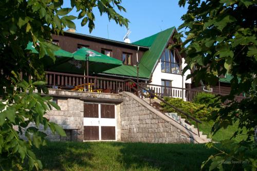 a building with a green roof and a patio at Penzion Pohlednička in Benecko
