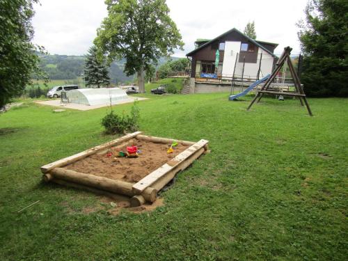 a sandbox in the middle of a yard with a playground at Penzion Pohlednička in Benecko