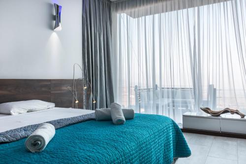 a bedroom with a bed with a blue blanket and a window at Oceania & Panorama Villas in Peyia