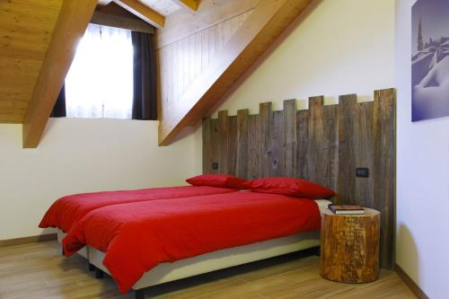 a bedroom with a red bed with a wooden headboard at Residence Hotel Anna in Passo del Tonale