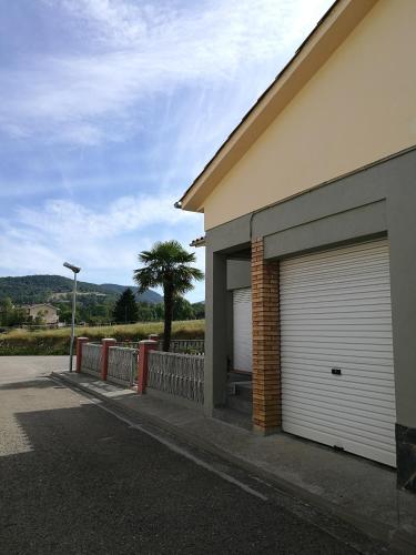 un edificio con dos puertas de garaje y una palmera en Casa El Serrat del Tell, en Sant Pau de Segúries