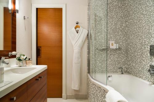
a bathroom with a shower, sink, and tub at Hôtel Barrière Le Normandy in Deauville
