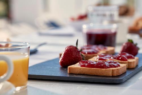 a plate of toast with strawberries and a glass of orange juice at Mr and Mrs White Paros in Naousa