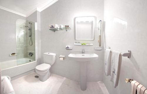 La salle de bains blanche est pourvue d'un lavabo et de toilettes. dans l'établissement Hotel Ancora SANXENXO, à Granxa
