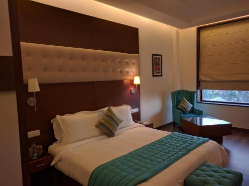 a bedroom with a large bed and a window at RS Sarovar Portico in Pālampur