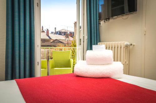 a stack of towels on a bed in a room with a window at Best Western Hôtel de France in Bourg-en-Bresse