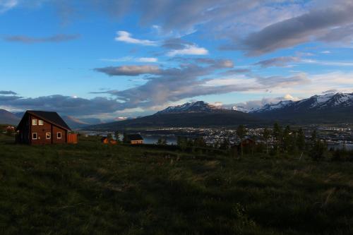 a house on a hill with mountains in the background at Akureyri Log Cottage in Akureyri