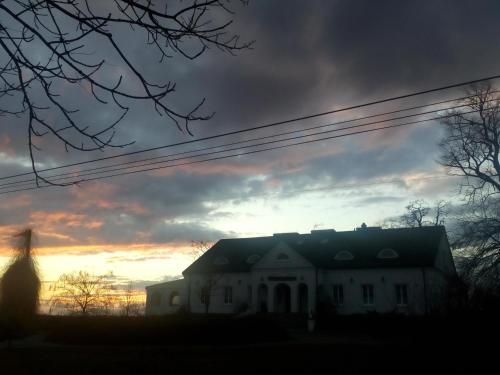 a house with the sunset in the background at Dwór na Wichrowym Wzgórzu in Przybysławice