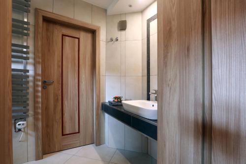 a bathroom with a sink and a wooden door at Wellness Penzion Pod Rozhlednou in Kostelec nad Orlicí
