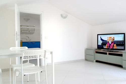 a white living room with a television and a table and chair at Residence Reale in Porto Azzurro