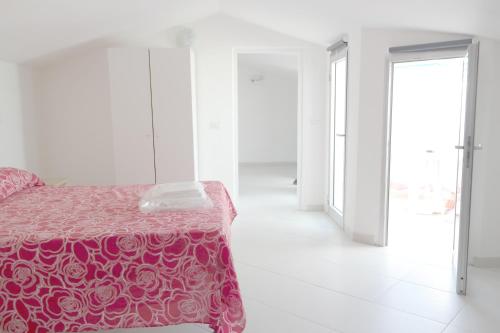 a white room with a bed with a pink blanket at Residence Reale in Porto Azzurro