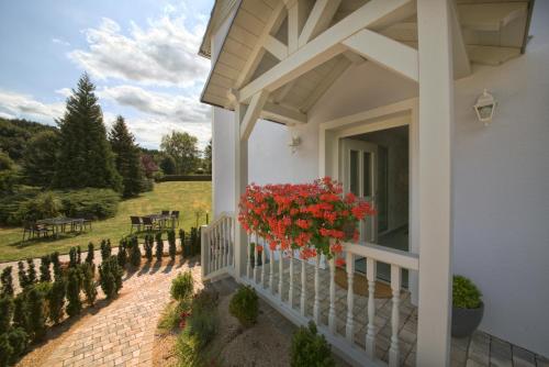 a white house with a balcony with red flowers at Hotel Jägerhof in Staatsbad Brückenau
