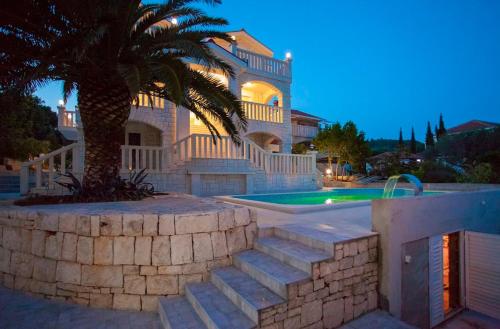a house with a palm tree and a swimming pool at Villa Drinka Apartments in Vela Luka