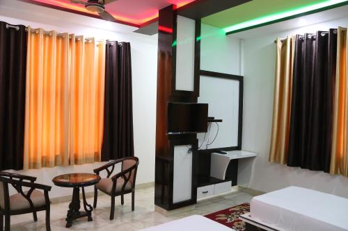 a living room with a tv and a table and chairs at Hotel Dhanraj Palace in Bharatpur