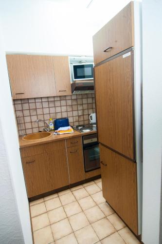 a small kitchen with wooden cabinets and a sink at Ferienapartments Schnibbe in Bad Lauterberg