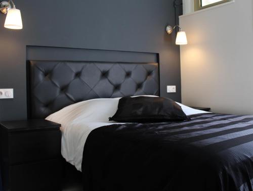 1 dormitorio con 1 cama grande y cabecero negro en Appart'hôtel et chambres Lens en Lens