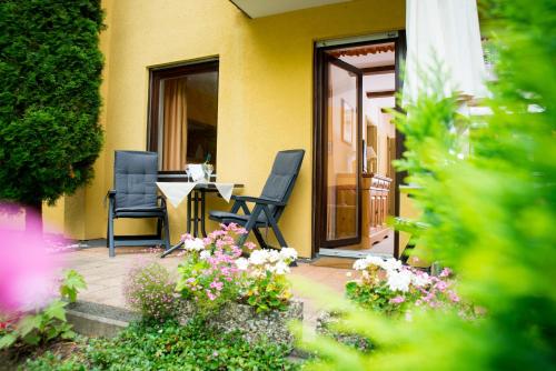 a patio with two chairs and a table and flowers at Ferienapartments Schnibbe in Bad Lauterberg