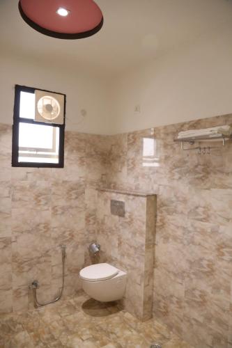 a bathroom with a toilet and a window at Hotel Dhanraj Palace in Bharatpur