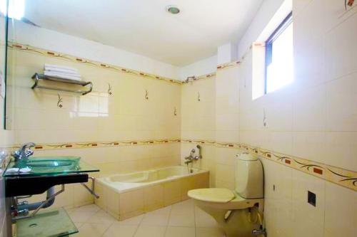 a bathroom with a tub and a toilet and a sink at Green Park Residency in Kannur