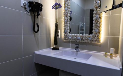 a bathroom with a sink and a mirror and a phone at Hôtel de la Tabletterie in Méru