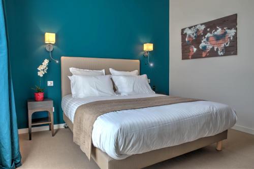 a bedroom with a large bed with blue walls at Hôtel de la Tabletterie in Méru