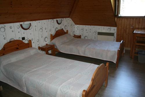 Duas camas num quarto com paredes de madeira em Gite Fouga em Aragnouet