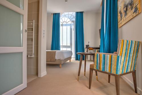 a bedroom with blue curtains and a chair and a bed at Hôtel de la Tabletterie in Méru