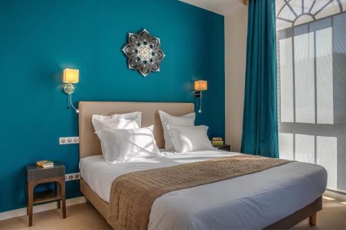 um quarto azul com uma cama com almofadas brancas em Hôtel de la Tabletterie em Méru